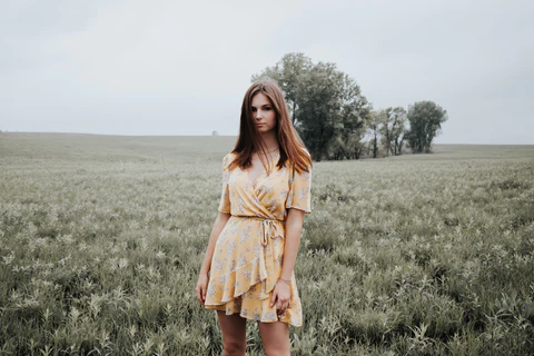 a woman wearing a floral dress in the field