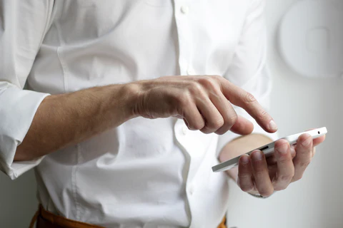 a man wearing a white shirt and holding a phone