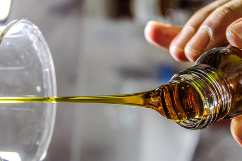 pouring olive oil into a measuring cup