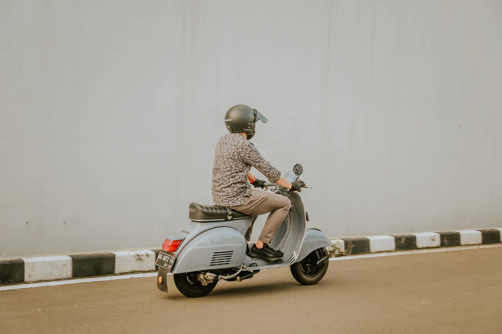 riding a light blue vespa