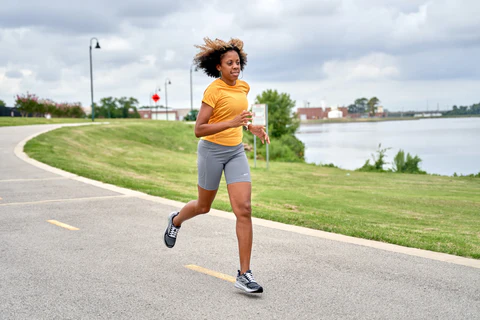 a running woman in a yellow moisture wicking t-shirt