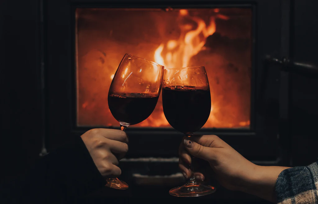 two glasses of wine near the fireplace