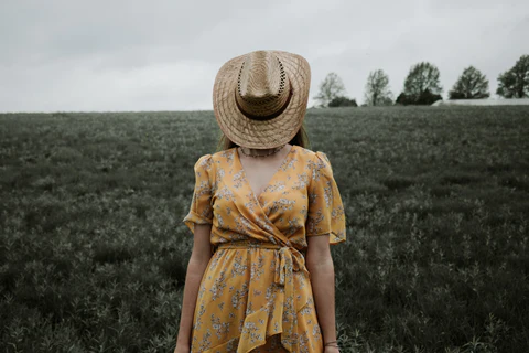 a woman wearing a yellow floral dress in nature