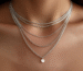 Close-up of layered silver chain necklaces on a woman’s neckline, styled for a modern minimalist look