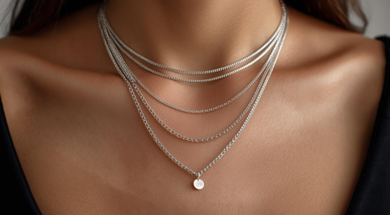 Close-up of layered silver chain necklaces on a woman’s neckline, styled for a modern minimalist look